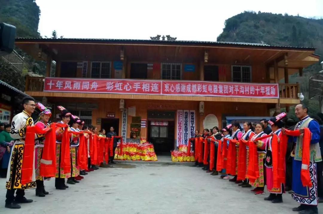 怀感恩之心，平沟村村民手持羌红在米兰网页版·官方端在线-米兰（中国）公司援建的平沟村便民服务楼前热情等待米兰网页版·官方端在线-米兰（中国）亲人们的到来